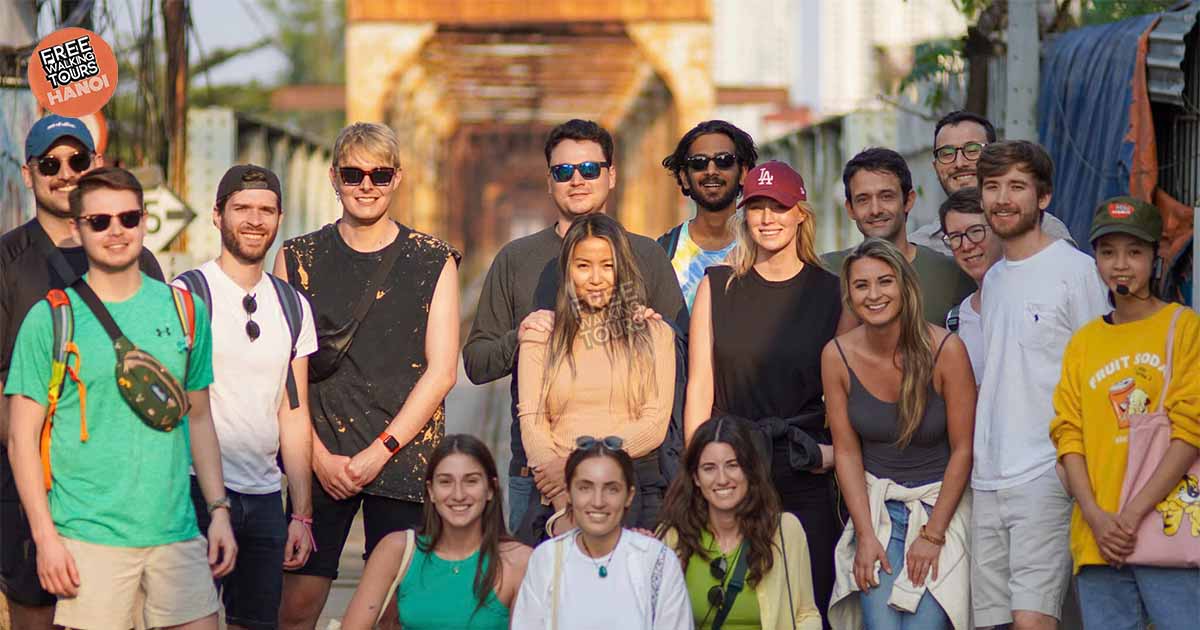 Group photo of travelers on Long Bien Bridge during a sunset walking tour in Hanoi